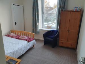 a bedroom with a bed and a chair and a window at Alastrean Flat in Aberdeen