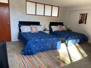 a bedroom with two beds with blue sheets and a rug at CasaHotel Laguna Jauja Airport in Jauja