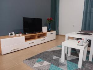 una sala de estar con TV en un centro de entretenimiento blanco en Apartman KLM, en Pančevo