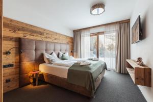 sypialnia z dużym łóżkiem i oknem w obiekcie Mulk Hotel - Joker Card included in Summer w Saalbach Hinterglemm
