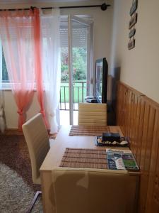 a living room with a table and chairs and a television at Dorka apartman in Vonyarcvashegy