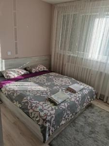 ein Schlafzimmer mit einem Bett mit einer Decke und einem Fenster in der Unterkunft Markoni in Sliven