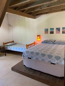 1 dormitorio con 2 camas y una lámpara en la pared en Quinta do Urutau, en Praia do Rosa