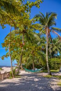 a hammock between two palm trees on a beach at Pousada Vila Palma Boipeba in Ilha de Boipeba