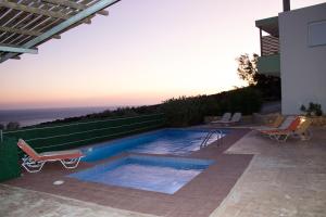 una piscina con 2 sillas junto a una casa en Paterakis Studios Triopetra, en Triopetra