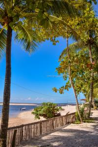 a beach with palm trees and the ocean at Pousada Vila Palma Boipeba in Ilha de Boipeba