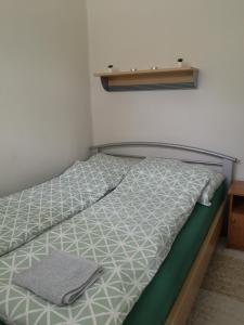 a bed with a green and white comforter on it at Dorka apartman in Vonyarcvashegy