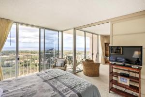 een slaapkamer met een bed, een tv en een balkon bij Makaha Condo Near Pokai Bay Beach with Ocean View! in Waianae