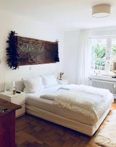 Un dormitorio con una cama grande con sábanas blancas y una ventana. en Auszeit, en Überlingen