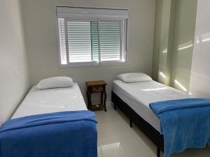 2 camas en una habitación pequeña con ventana en 1053 - Praia de Bombinhas locação de temporada - Residencial Egídio Pinheiro Apto 302 B, en Bombinhas