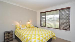 a bedroom with a yellow and white bed and a window at Sunnyvale unit 1 in Yamba
