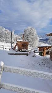 un patio cubierto de nieve con una cesta de madera en la nieve en Cabana Himalaya Lodge cu ciubăr din inima munților Apuseni- masivul Buces -Vulcan, 