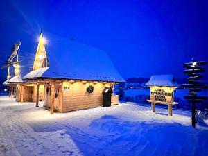 een klein gebouw met een kerstboom in de sneeuw bij Domki Tatrzańskie Kącina in Murzasichle