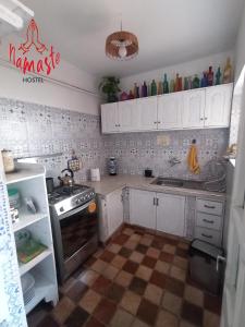 a kitchen with white cabinets and a stove top oven at Namaste Hostel in Tarija