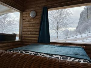 a bed in a room with a window and a clock at Cabana Himalaya Lodge cu ciubăr din inima munților Apuseni- masivul Buces -Vulcan 