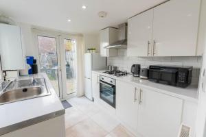 a white kitchen with a sink and a microwave at 2 bedroom house with free Parking, Aylesbury, Johns st in Buckinghamshire