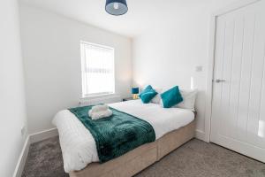 a white bedroom with a large bed with blue pillows at 2 bedroom house with free Parking, Aylesbury, Johns st in Buckinghamshire