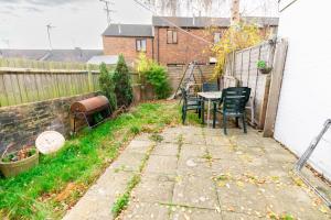einen Hinterhof mit einem Tisch, Stühlen und einem Zaun in der Unterkunft 2 bedroom house with free Parking, Aylesbury, Johns st in Buckinghamshire
