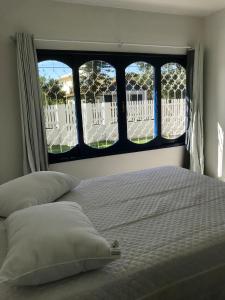 1 cama con 2 almohadas en un dormitorio con ventana en Residencial Casa da Vila apto 3, en Imbituba