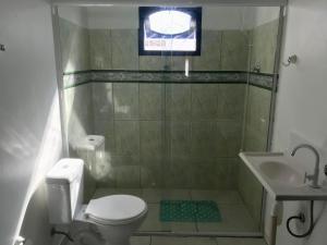 y baño con aseo y lavamanos. en Residencial Casa da Vila apto 3, en Imbituba