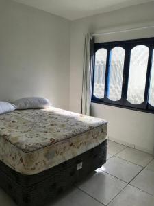 1 cama en una habitación con 2 ventanas en Residencial Casa da Vila apto 3, en Imbituba