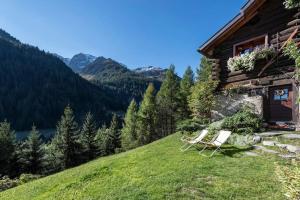 um par de cadeiras sentadas ao lado de uma casa em "CHALET dei FIORI" room & apartment em Bedretto