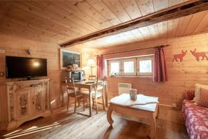 ein Wohnzimmer mit einem Tisch und einem TV in einer Hütte in der Unterkunft "CHALET dei FIORI" rooms in Bedretto