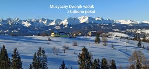 una ladera cubierta de nieve con una casa y montañas en Muzyczny Dworek en Rzepiska