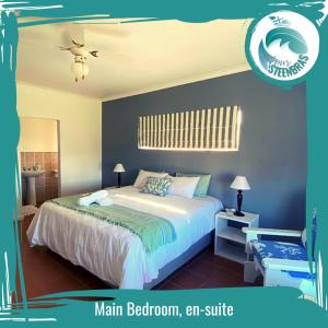 a bedroom with a king sized bed with blue walls at Four Steenbras in Struisbaai