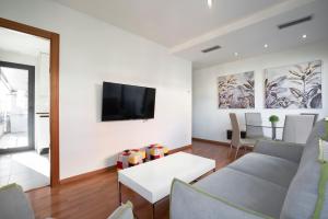 sala de estar con sofá y TV en la pared en EnjoyGranada LUJO Piscina y Parking, en Granada
