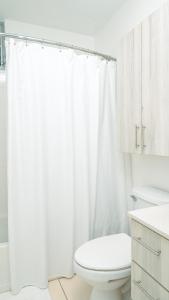a white bathroom with a toilet and a shower curtain at Modern Beach Walk at Puerto Bahia #30 in Rincon
