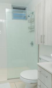 a white bathroom with a toilet and a shower at Modern Beach Walk at Puerto Bahia #30 in Rincon