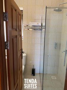 a bathroom with a toilet and a glass shower at Tenda Suites and Restaurant in Entebbe