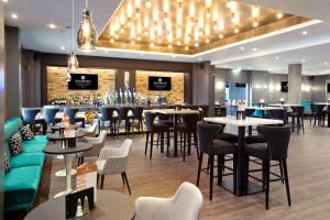 a restaurant with tables and chairs and a bar at Sandman Signature London Gatwick Hotel in Crawley