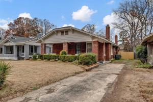 a brick house with a driveway in front of it at Contemporary Cottage near zoo and Rhodes college in Memphis