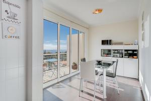 a white kitchen with a table and chairs and a balcony at Anje Apartamento in Funchal