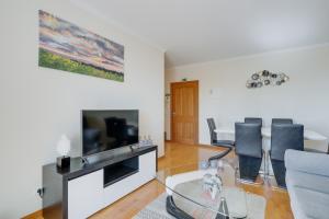a living room with a tv and a table with chairs at Anje Apartamento in Funchal