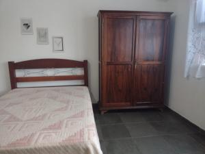 1 dormitorio con 1 cama y armario de madera en Kit ótima localização - Águas de Lindoia, en Águas de Lindóia