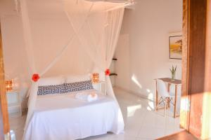 a bedroom with a white bed with a mosquito net at Pousada Vila Palma Boipeba in Ilha de Boipeba