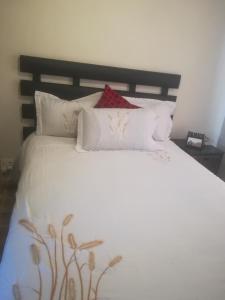 1 cama blanca grande con 4 almohadas en TLZ Prop B&B, en Pretoria
