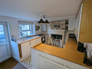 uma cozinha com armários brancos e um balcão de madeira em Rush Hill Cottage - with parking for 2 cars em Bath