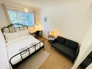 a bedroom with a bed and a couch and a window at Greenwich Apartments by Sleepy in London