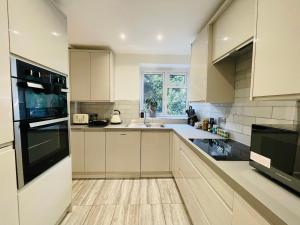 a kitchen with white cabinets and a black appliance at Greenwich Apartments by Sleepy in London