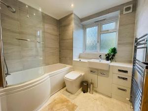 a bathroom with a tub and a toilet and a sink at Greenwich Apartments by Sleepy in London