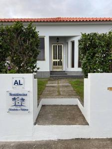 une maison blanche avec un panneau devant elle dans l'établissement Casa das Palmeiras - Res. of Elizabete and Fatima, à Horta