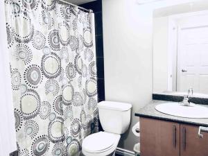 a bathroom with a toilet and a shower curtain at 2 BDRM A/C Condo w/Ensuite Laundry + Free Parking in Edmonton +17 photos