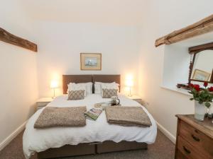 a bedroom with a large bed and two lamps at Brook Cottage in Stearsby