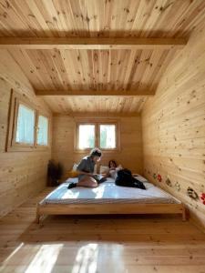 duas pessoas deitadas numa cama num quarto de madeira em BeeHouse - La Casa delle Api Agriturismo em Borso del Grappa