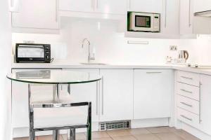 a white kitchen with a table and a microwave at Sandman Signature Newcastle in Newcastle upon Tyne