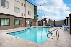 una piscina con sillas azules y un edificio en Motel 6-Pharr, TX, en Pharr